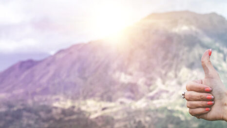 Woman giving thumbs up with a mountain in the background